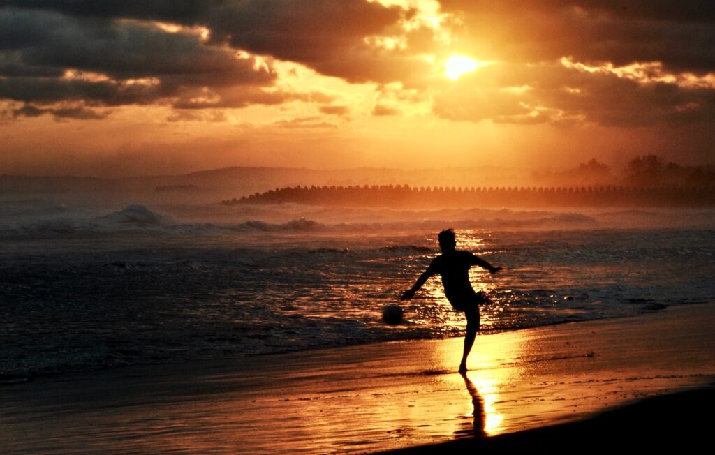 guy playing soccer at sunset