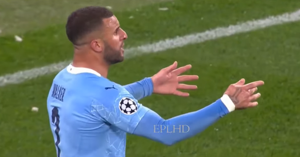 Kyle Walker gesturing with his hands in a blue football t-shirt on the field