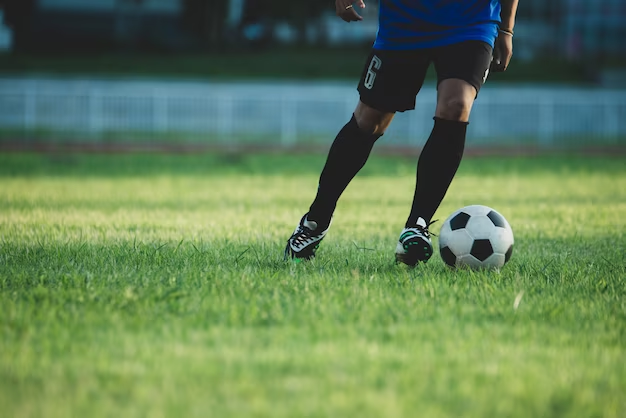 Person playing football on the field with the ball at his feet